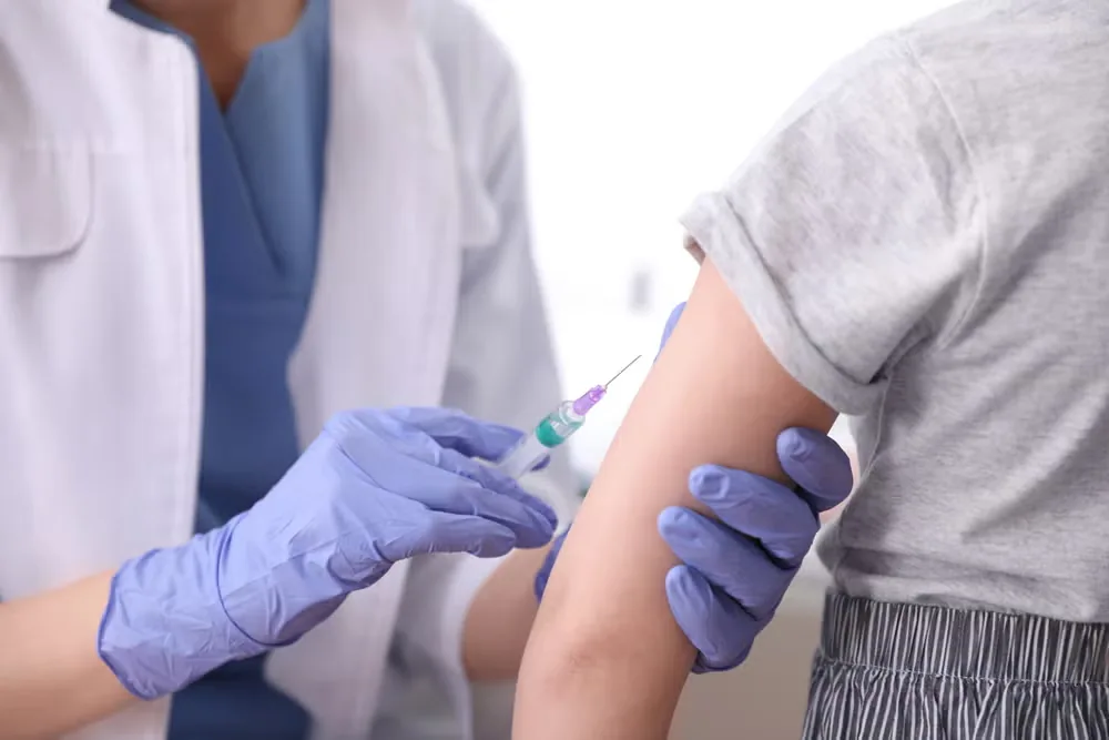 Clinician giving a child a vaccination in the upper arm