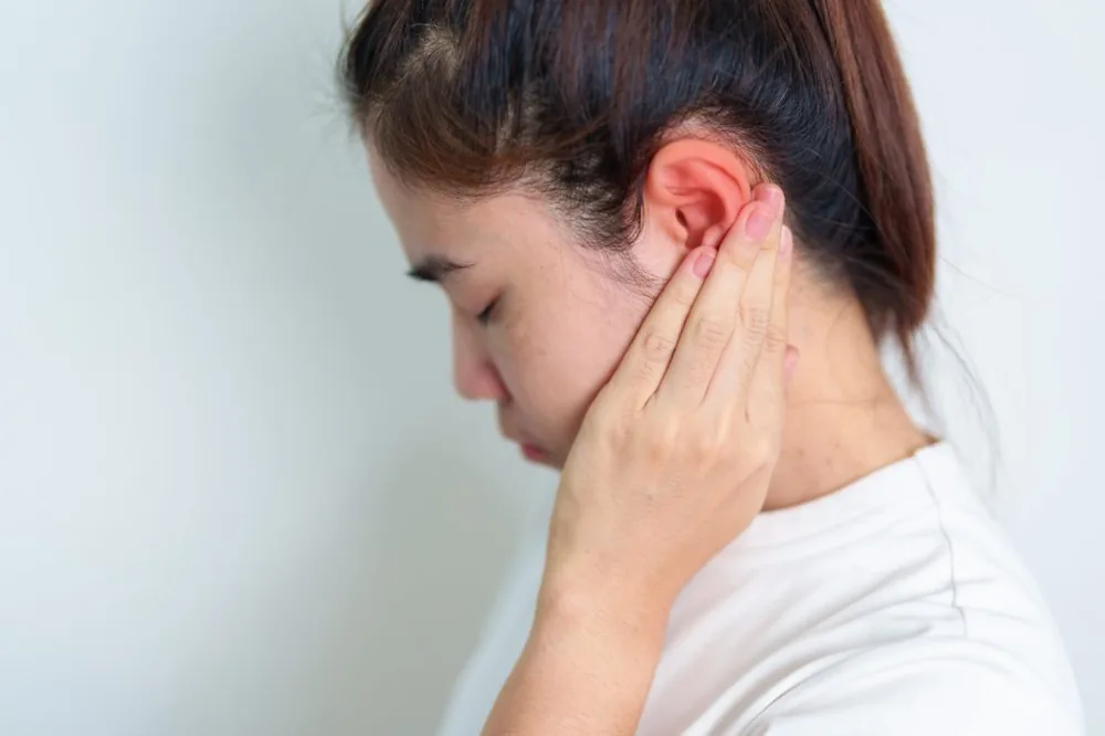 Young woman holding her ear in discomfort