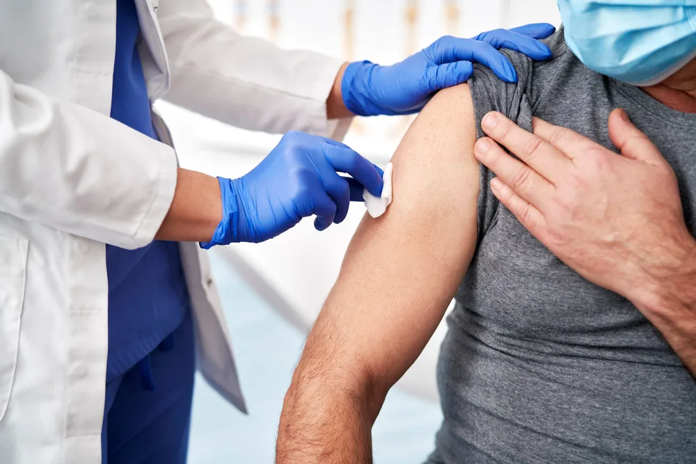 Clinician cleaning a patient’s arm before giving a flu vaccination