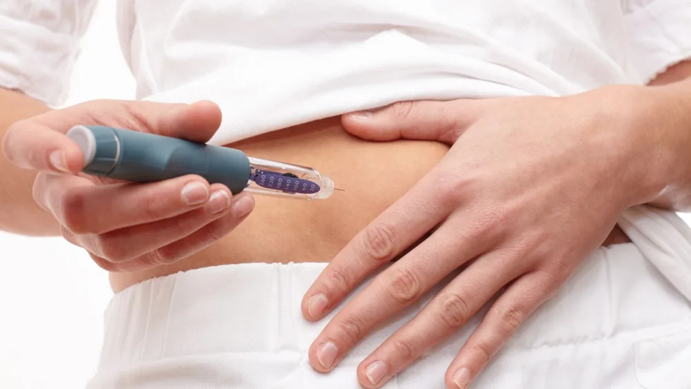 Person injecting into the abdomen using a pre-filled injector pen